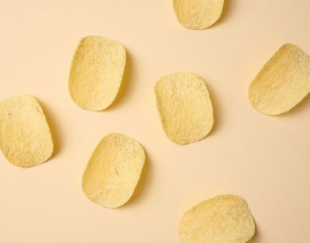 Round potato chips on a beige background, top view