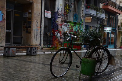 Bicycle parked on wet footpath against building