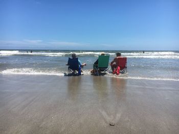 People on beach against clear sky