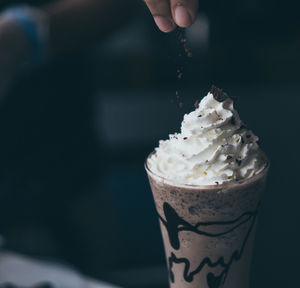 Cropped hand of person sprinkling chocolate on dessert