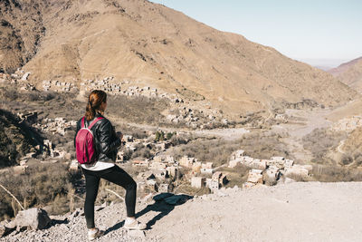 Rear view of woman standing on mountain against sky