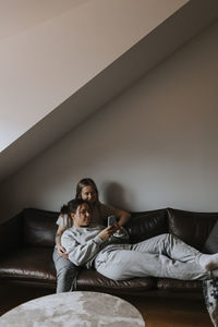 Female couple relaxing together on sofa and looking at cell phone