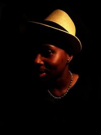 Close-up of young woman against black background