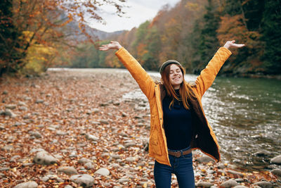 Full length of young woman standing by tree