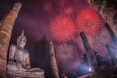 Statue of illuminated buddha against sky at night