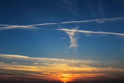 Scenic view of cloudy sky with vapor trails during sunset