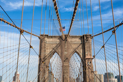 Low angle view of suspension bridge against cloudy sky