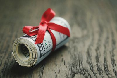 Close-up of rolled paper currency tied with ribbon on table