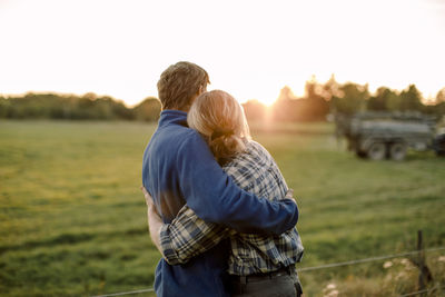 Couple hugging each other on field during sunset