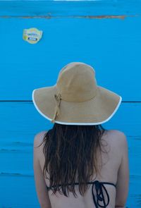 Rear view of woman wearing hat against blue sea