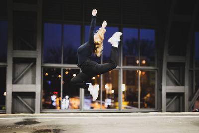 Side view of woman with arms raised jumping indoors