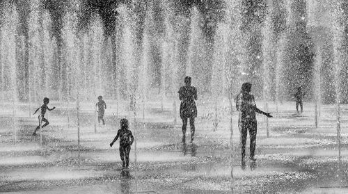 Silhouette people enjoying fountains