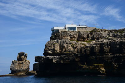 Rock formation by sea against sky