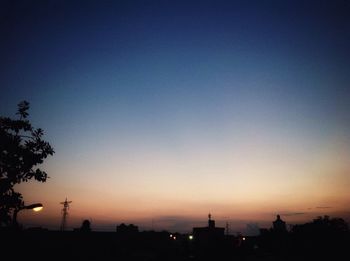 Silhouette trees against clear sky at sunset