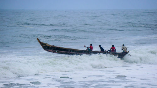 People on boat in sea against sky