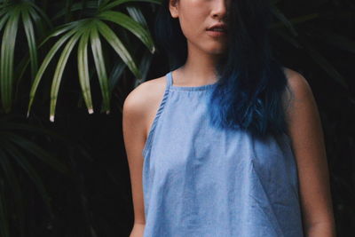 Midsection of young woman standing by plants