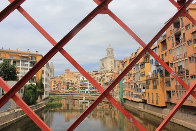 Buildings and canal in city seen through fence