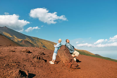 Tourist woman and man enjoying freedom, while admiring panoramic view of volcano etna.