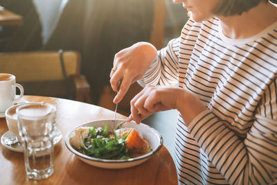 Young woman has healthy breakfast at table in morning cafe