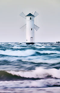 Lighthouse by sea against sky