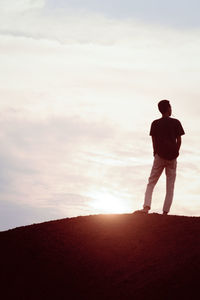 Rear view of silhouette man standing on field against sky