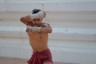 Portrait of shirtless man standing against blurred background