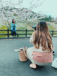 Woman photographing while sitting outdoors