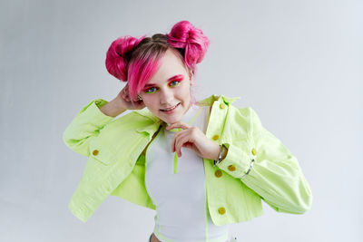 Portrait of young woman standing against white background