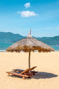 Deck chairs on beach against sky