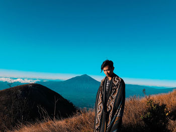 Portrait of young man standing against clear blue sky