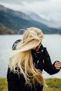 Young woman standing against lake