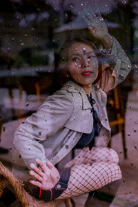 Woman looking away seen through wet glass window
