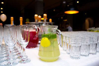 Soft drinks lemonades in large glass jugs on the table surrounded with empty glasses