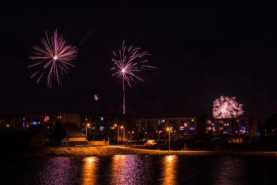 Firework display over river against sky at night