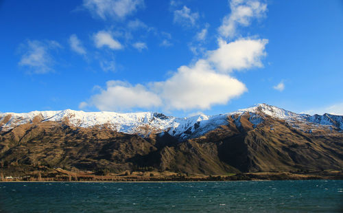 Scenic view of sea and snowcapped mountains against sky