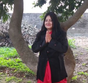 Portrait of smiling young woman standing against trees