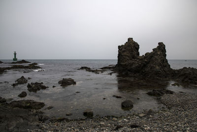 Rock formation on beach against clear sky