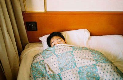 High angle portrait of man lying on bed at home