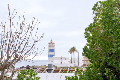 Lighthouse by sea against sky