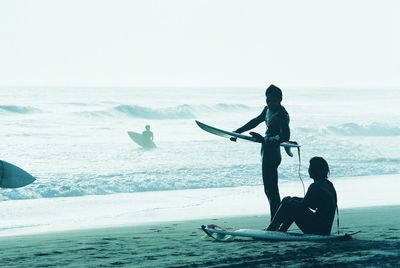 Silhouette of people with surfboards on beach