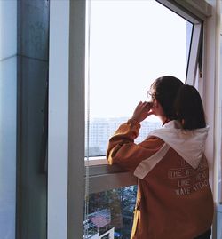 Side view of woman drinking glass window