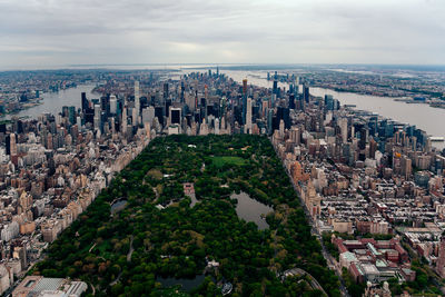 High angle view of city buildings against cloudy sky