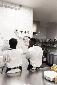 Male and female colleagues planning over whiteboard at restaurant kitchen