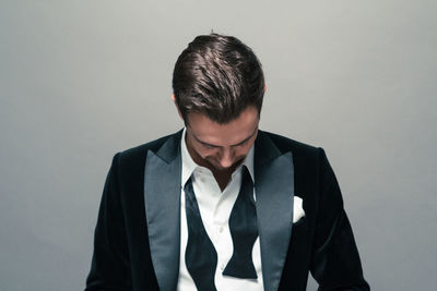 Sad young man in suit against gray background