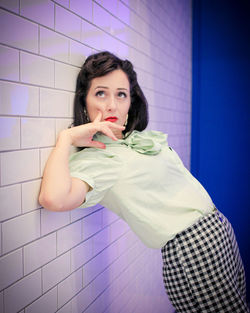 Portrait of young woman standing against wall