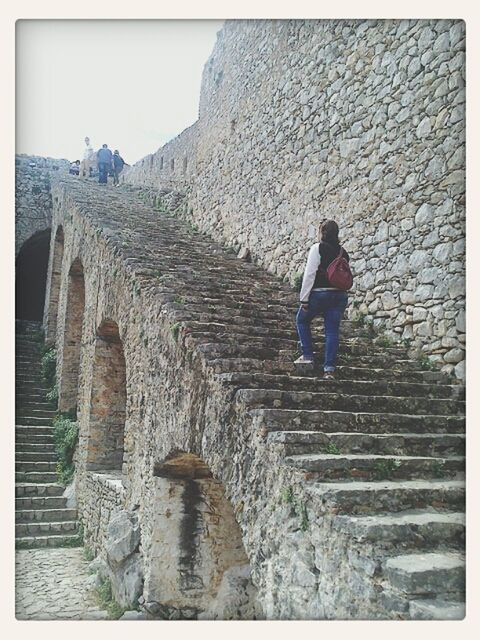 steps, architecture, built structure, building exterior, lifestyles, stone wall, steps and staircases, leisure activity, full length, staircase, men, person, transfer print, history, auto post production filter, walking, brick wall, rear view