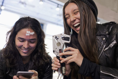 Portrait of smiling young woman photographing while using smart phone