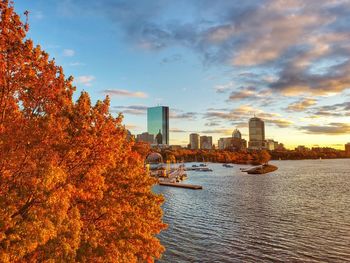 Scenic view of river by buildings against sky during autumn