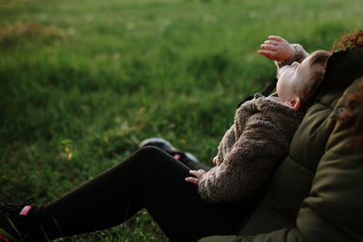 Rear view of mother and daughter on grass against sky