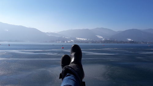 Rear view of man on sea against mountain range